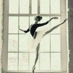 a ballerina is standing in front of a window