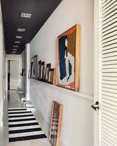 a long hallway with pictures on the wall and framed artwork hanging on the wall next to it