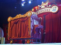 the stage is decorated with red curtains and gold trimmings as well as an elaborate bed