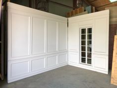 an empty room with white paneling and windows