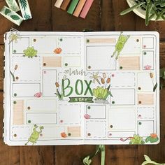 an open planner book sitting on top of a wooden table next to markers and pencils