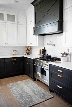 a kitchen with black and white cabinets, gold pulls on the range hoods in front of an oven