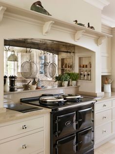 a kitchen with an old fashioned stove and oven in it's center island, surrounded by white cabinets