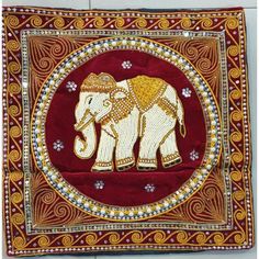 an intricately decorated wall hanging with an elephant on it's side, in gold and red