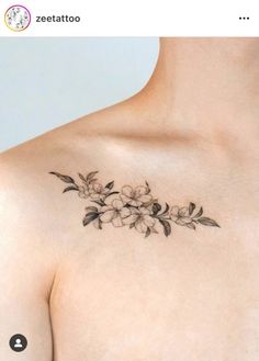 a woman's chest with flowers and leaves tattooed on the top of her breast