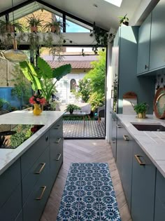 an open kitchen with blue and white tiles on the floor, plants in pots hanging from the ceiling