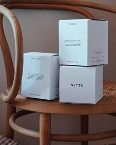 three white boxes sitting on top of a wooden chair next to a brown wicker chair