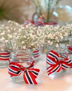 small mason jars filled with baby's breath flowers and red white and blue ribbons