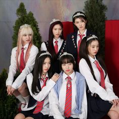 a group of young women in school uniforms posing for a photo together on a red couch