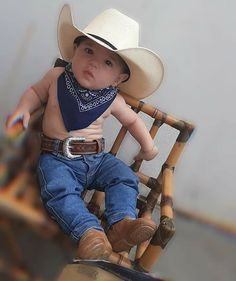 a baby wearing a cowboy hat sitting in a chair