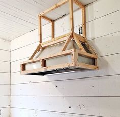 a light fixture made out of wood hanging from the side of a white shiplap wall