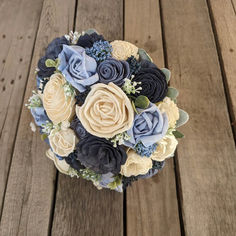 a bridal bouquet with blue and yellow flowers on a wooden floor in the sun