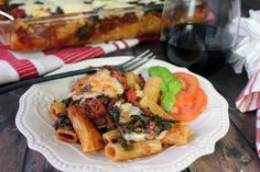 a white plate topped with pasta and vegetables next to a casserole dish on a wooden table