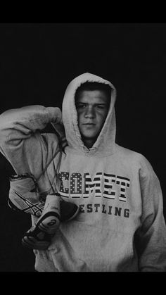 a black and white photo of a man in a hoodie holding a baseball glove