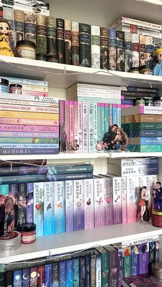 several books are stacked on the shelves in a book store, with one person standing next to them