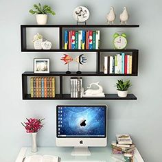 an apple computer sitting on top of a desk in front of a book shelf filled with books