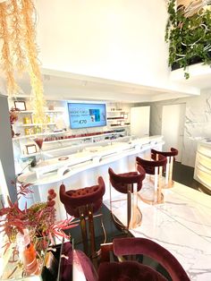 the interior of a restaurant with red velvet chairs and bar stools in front of it