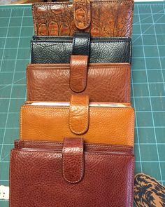 four leather wallets sitting on top of a cutting board