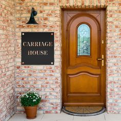 a wooden door with a sign that says carriage house next to a potted plant