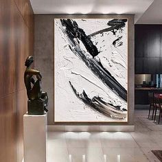 an abstract painting hangs on the wall next to a statue in a modern living room