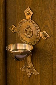 a metal bowl on a wooden door with a cross and emblem in the middle,