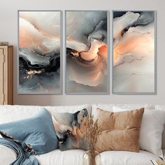 three paintings hanging on the wall above a couch in a room with white furniture and pillows