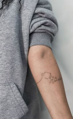 a woman's arm with a small dog tattoo on the left side of her arm