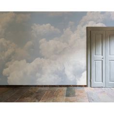 an open door in front of a wall with clouds painted on it