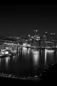 a black and white photo of a city at night with lights in the water below