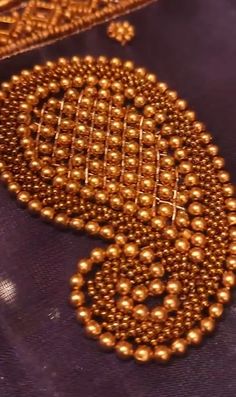 some gold beads are laying on a purple cloth