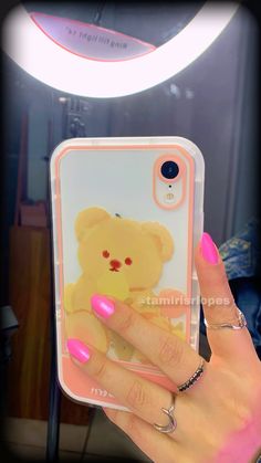 a person holding up a phone case with a teddy bear on it