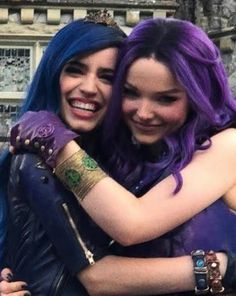 two young women hugging each other in front of a building with blue hair and bracelets