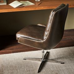 a brown leather office chair sitting on top of a rug next to a wooden desk