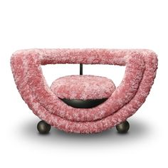 a pink chair with wooden legs and a round cushion on the bottom, in front of a white background