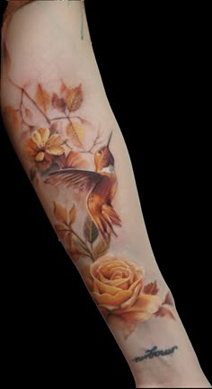 a tattoo with flowers and a bird on it's arm, in front of a white background