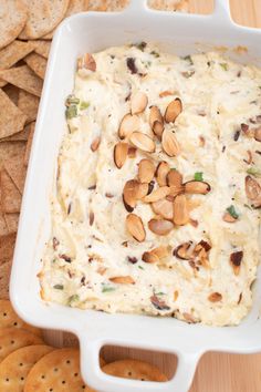 a white dish filled with dip surrounded by crackers