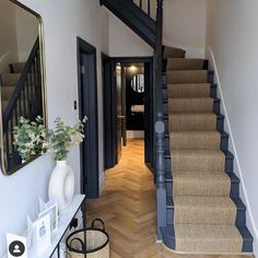 an entry way with stairs, mirror and vase on the side table in front of it