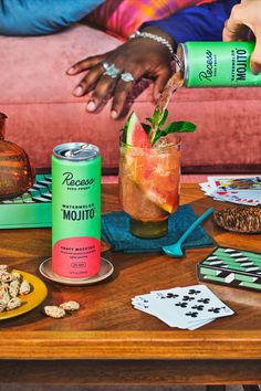 a person is pouring something into a glass on a table next to other drinks and snacks