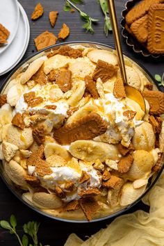 a bowl filled with bananas and cream on top of a wooden table next to plates