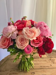 a vase filled with lots of pink and red flowers