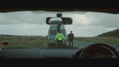 two police officers standing next to a van on the side of the road in front of a car