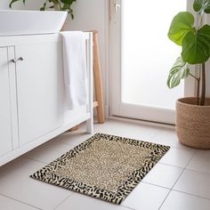 a bathroom with a plant and rug on the floor