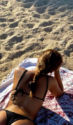 a woman laying on top of a beach towel