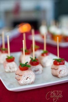 small appetizers are arranged on a plate with toothpicks in the shape of tomatoes