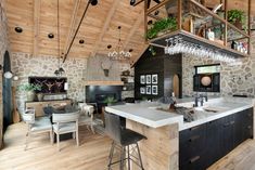 an open concept kitchen and living room with stone walls, wood flooring and exposed ceiling