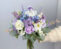 a person holding a bouquet of flowers in their hand with gloves on the other side