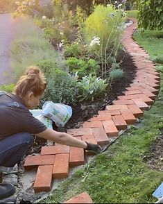 a woman is laying bricks on the ground