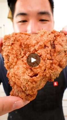 a man holding up a heart shaped cookie in front of his face with the video on it