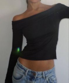 a woman in jeans is posing with her arms behind her back and one hand on her hip