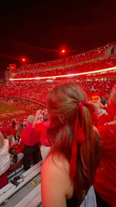 a crowd of people sitting in the stands at a baseball game with red lights on